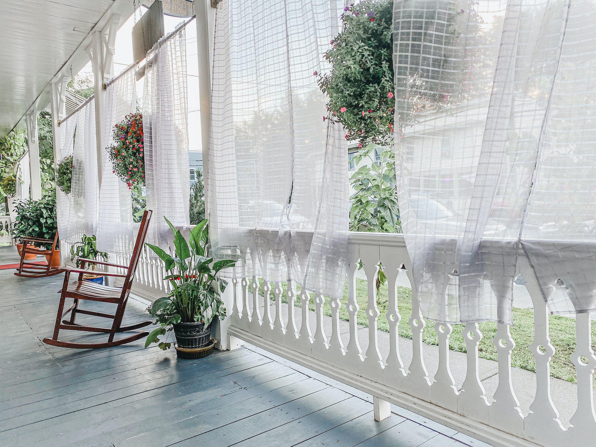 A beautiful summer breeze parts the curtains on an bright and expansive porch.