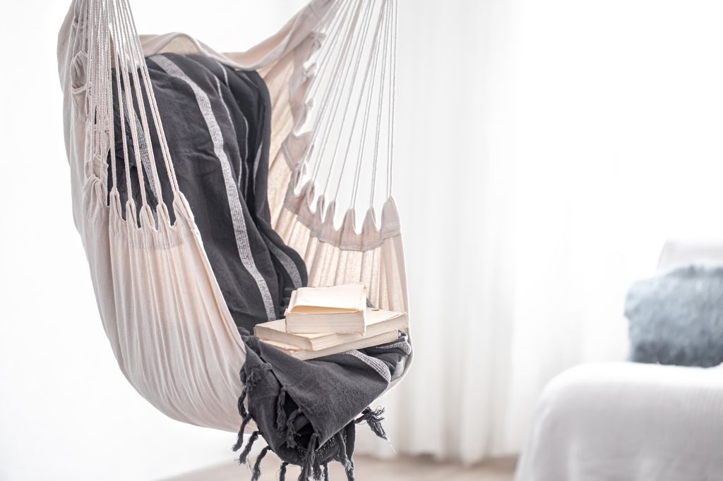 A boho-style hammock chair with a stack of books